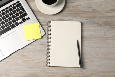 Photo of Notebook, pen, sticky note, coffee and laptop on wooden table, flat lay