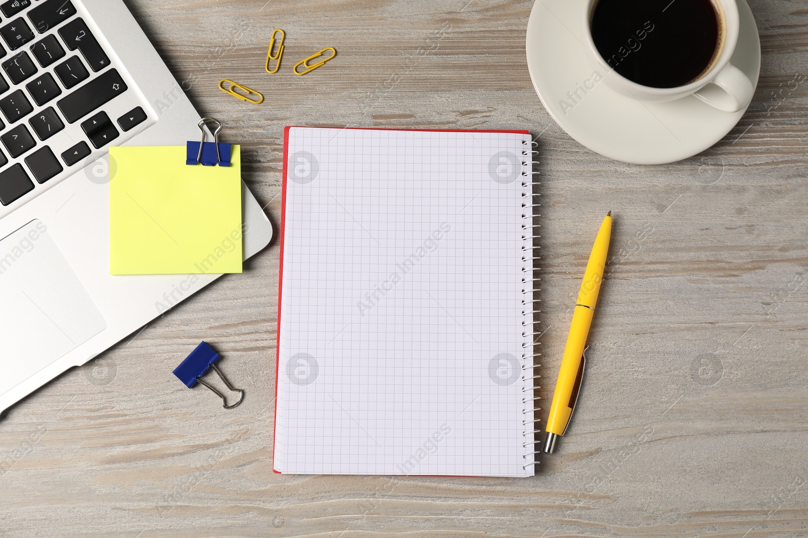 Notebook, other stationery, glasses, coffee and laptop on wooden table, flat lay Photo of Notebook, other stationery, glasses, coffee and laptop on wooden table, flat lay