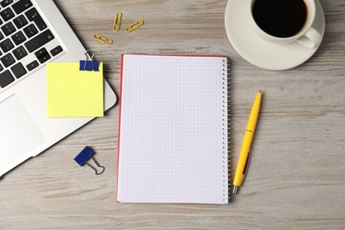Photo of Notebook, other stationery, glasses, coffee and laptop on wooden table, flat lay