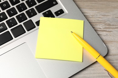 Photo of Sticky note, pen and laptop on wooden table, above view