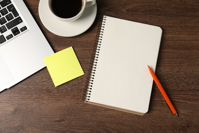 Photo of Notebook, pen, sticky note, coffee and laptop on wooden table, flat lay