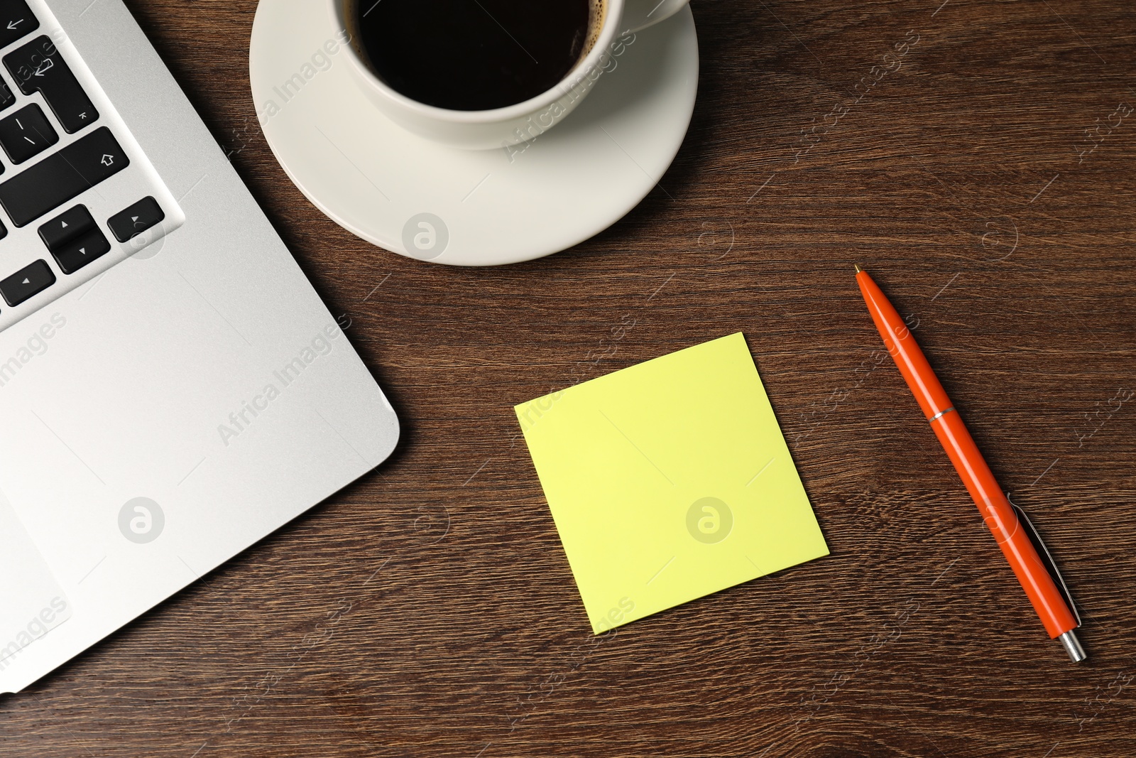 Sticky note, pen, coffee and laptop on wooden table, flat lay Photo of Sticky note, pen, coffee and laptop on wooden table, flat lay