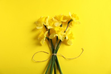 Photo of Bunch of beautiful daffodils on yellow background, top view