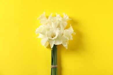 Photo of Bunch of beautiful daffodils on yellow background, top view