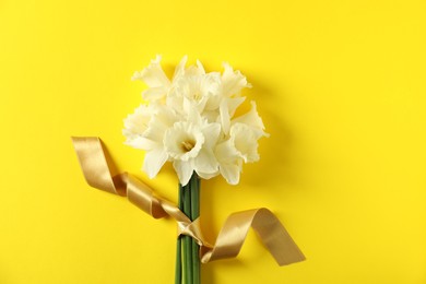 Photo of Bunch of beautiful daffodils on yellow background, top view