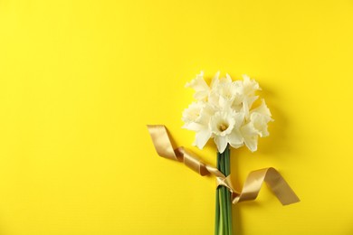 Photo of Bunch of beautiful daffodils on yellow background, top view. Space for text