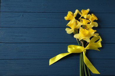 Photo of Bunch of beautiful daffodils on blue wooden table, top view. Space for text