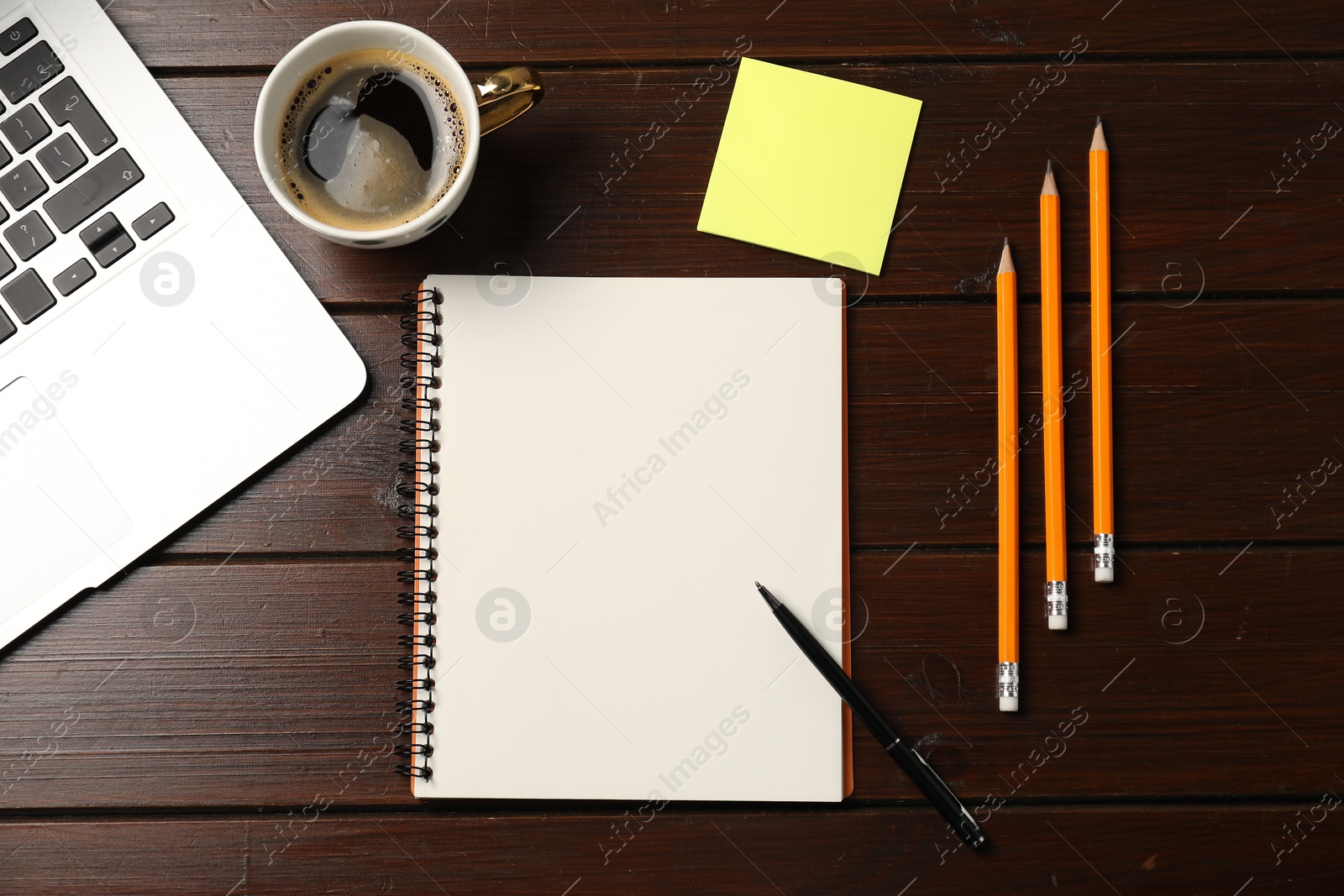 Notebook, pen, pencils, sticky note, coffee and laptop on wooden table, flat lay Photo of Notebook, pen, pencils, sticky note, coffee and laptop on wooden table, flat lay