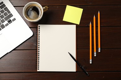 Photo of Notebook, pen, pencils, sticky note, coffee and laptop on wooden table, flat lay