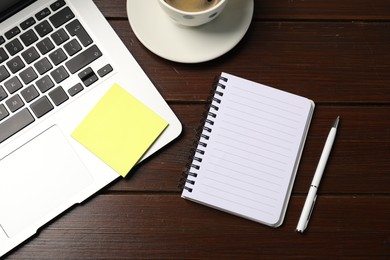 Photo of Notebook, sticky note, pen, coffee and laptop on wooden table, flat lay