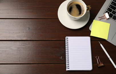 Photo of Notebook, sticky note, pen, binder clips, coffee and laptop on wooden table, flat lay. Space for text