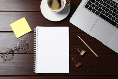 Photo of Notebook, sticky note, pen, binder clips, coffee, glasses and laptop on wooden table, flat lay