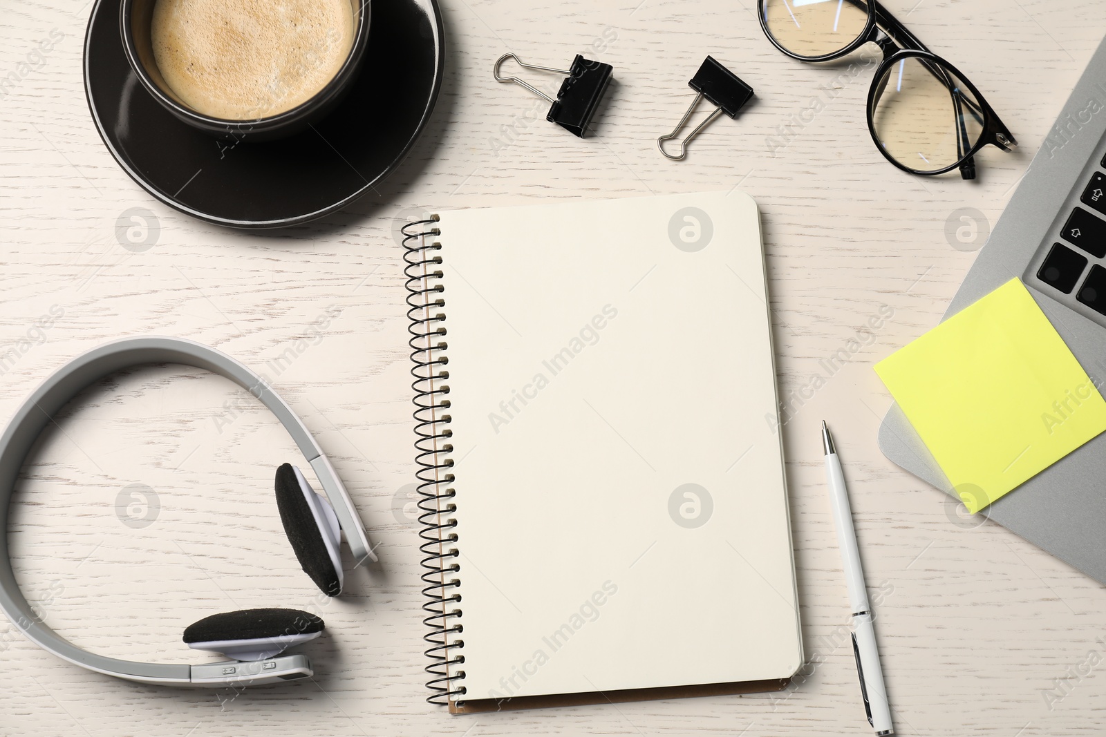 Notebook, pen, sticky note, glasses, coffee, headphones and laptop on white wooden table, flat lay Photo of Notebook, pen, sticky note, glasses, coffee, headphones and laptop on white wooden table, flat lay