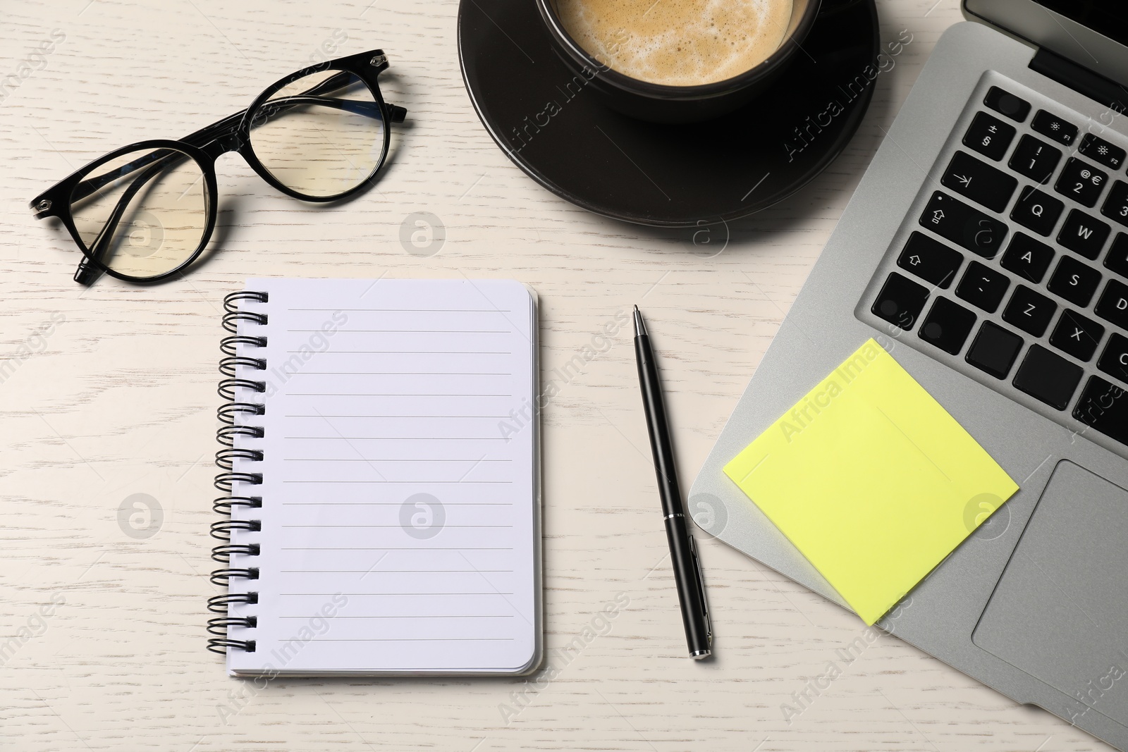 Notebook, pen, sticky note, glasses, coffee and laptop on white wooden table, flat lay Photo of Notebook, pen, sticky note, glasses, coffee and laptop on white wooden table, flat lay