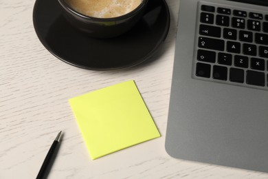 Photo of Sticky note, pen, coffee and laptop on white wooden table, above view