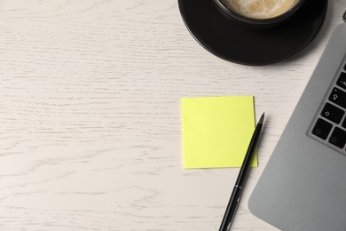 Photo of Sticky note, pen, coffee and laptop on white wooden table, above view. Space for text