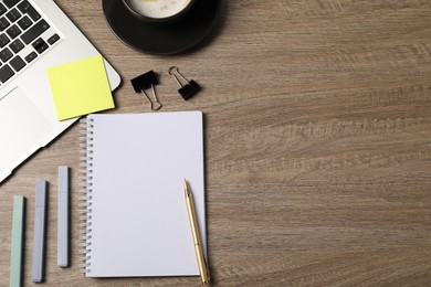 Photo of Notebook, other stationery, coffee and laptop on wooden table, flat lay. Space for text