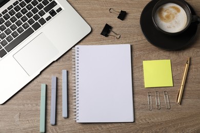 Photo of Notebook, other stationery, coffee and laptop on wooden table, flat lay