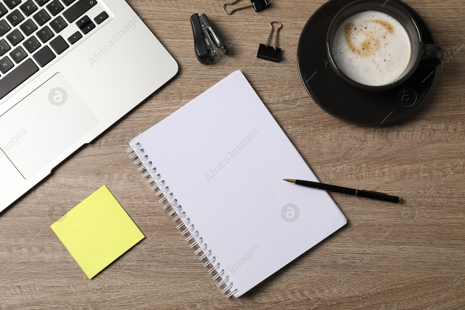 Notebook, other stationery, coffee and laptop on wooden table, flat lay Photo of Notebook, other stationery, coffee and laptop on wooden table, flat lay