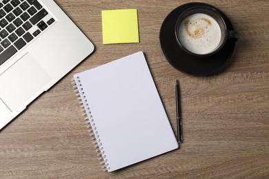 Photo of Notebook, sticky note, pen, coffee and laptop on wooden table, flat lay
