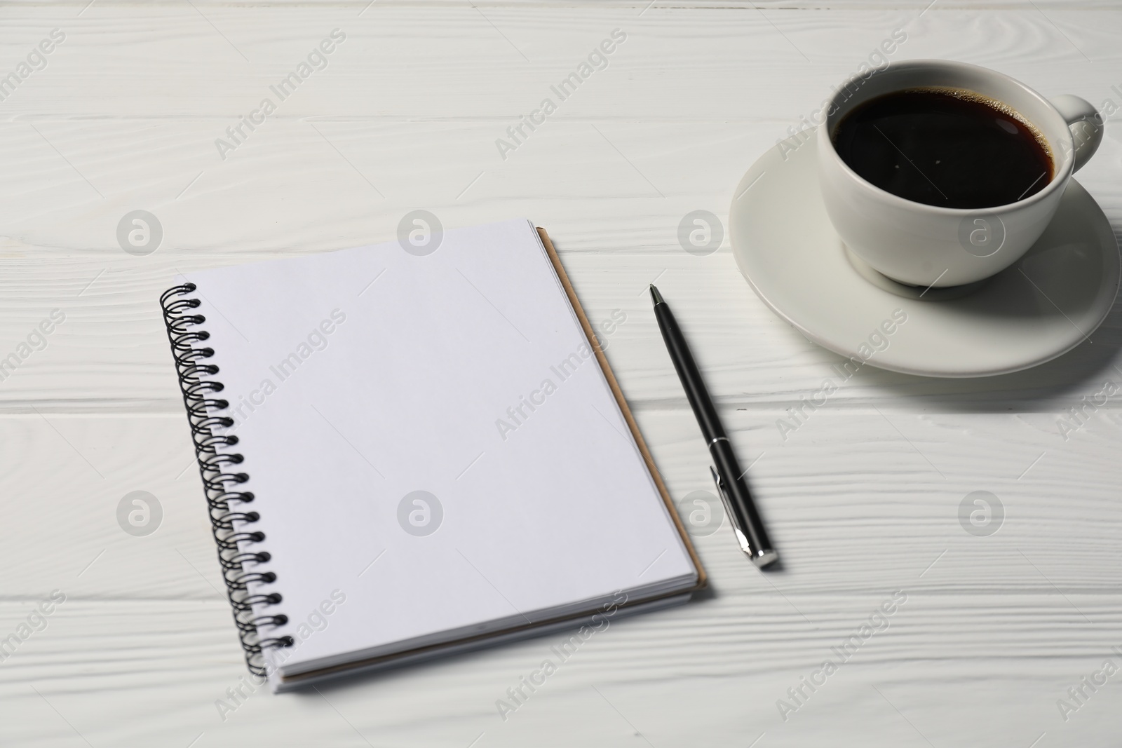 Notebook, pen and coffee on white wooden table, closeup Photo of Notebook, pen and coffee on white wooden table, closeup