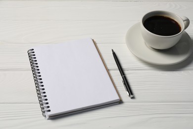 Photo of Notebook, pen and coffee on white wooden table, closeup