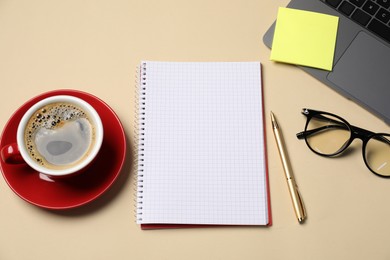 Photo of Notebook, sticky note, pen, coffee, glasses and laptop on beige background, flat lay