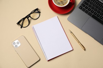 Photo of Notebook, pen, coffee, smartphone, glasses and laptop on beige background, flat lay