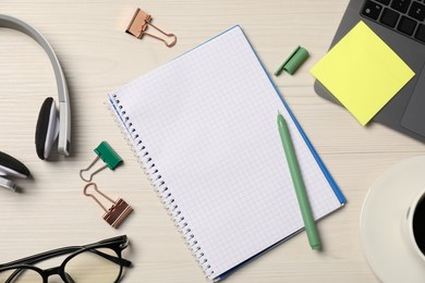 Photo of Notebook, other stationery, headphones, glasses and laptop on wooden table, flat lay