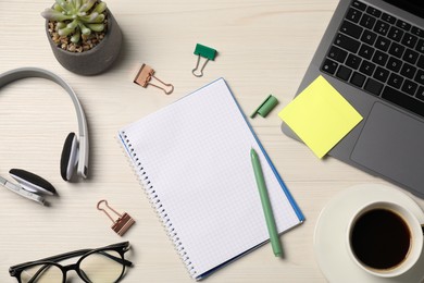 Photo of Notebook, other stationery, headphones, glasses, coffee, floral decor and laptop on wooden table, flat lay
