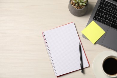 Photo of Notebook, sticky note, pen, coffee, floral decor and laptop on wooden table, flat lay. Space for text
