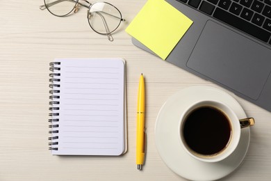 Photo of Notebook, pen, sticky note, glasses, coffee and laptop on wooden table, flat lay