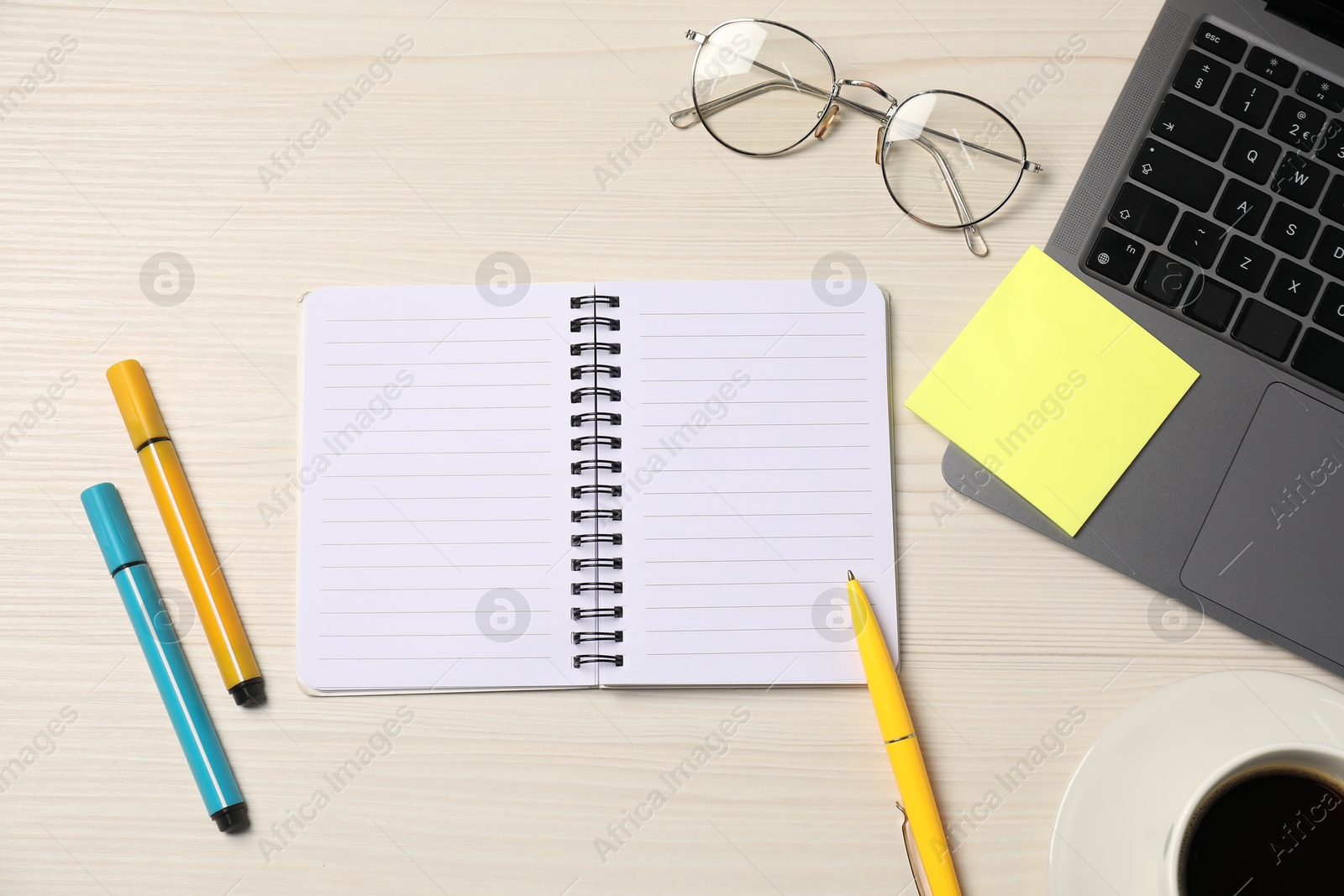 Notebook, sticky note, pen, markers, coffee, glasses and laptop on wooden table, flat lay Photo of Notebook, sticky note, pen, markers, coffee, glasses and laptop on wooden table, flat lay
