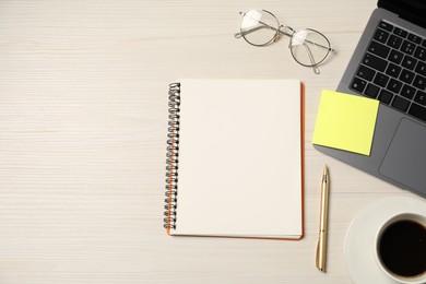 Photo of Notebook, pen, sticky note, glasses, coffee and laptop on wooden table, flat lay. Space for text