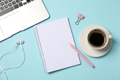 Photo of Notebook, pen, earphones, coffee, binder clip and laptop on light blue background, flat lay