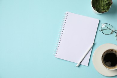 Photo of Notebook, pen, glasses, coffee and floral decor on light blue background, flat lay. Space for text