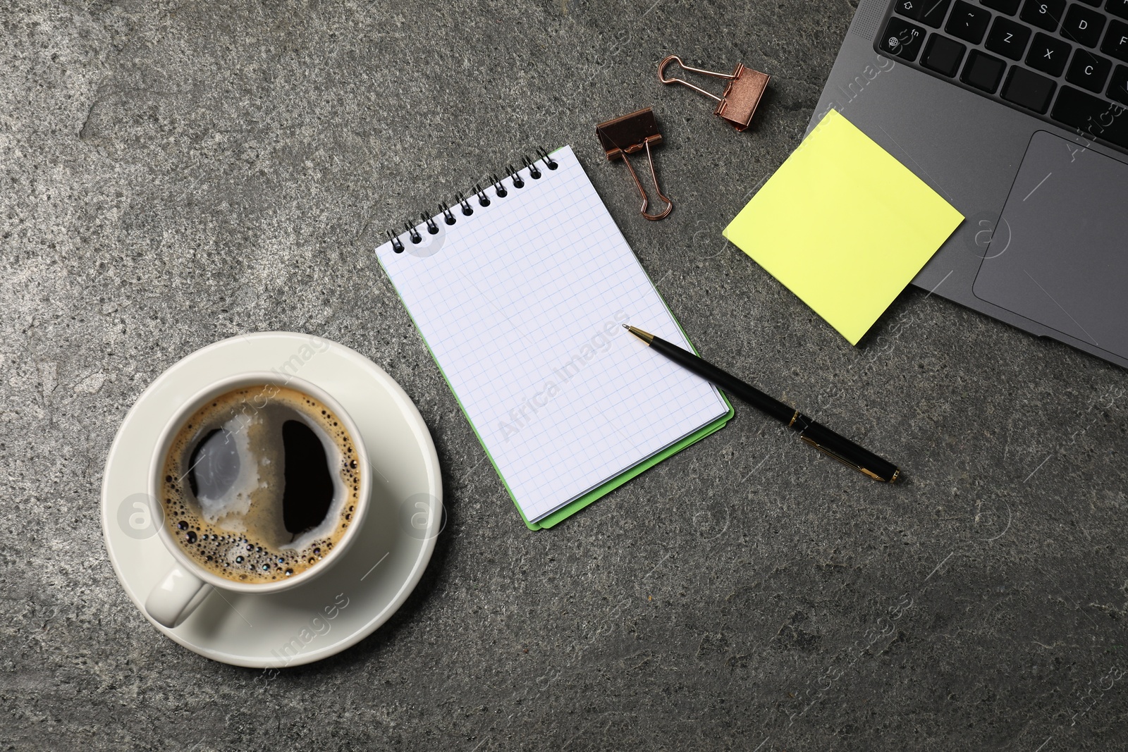 Notebook, pen, sticky note, coffee, binder clips, and laptop on grey table, flat lay Photo of Notebook, pen, sticky note, coffee, binder clips, and laptop on grey table, flat lay