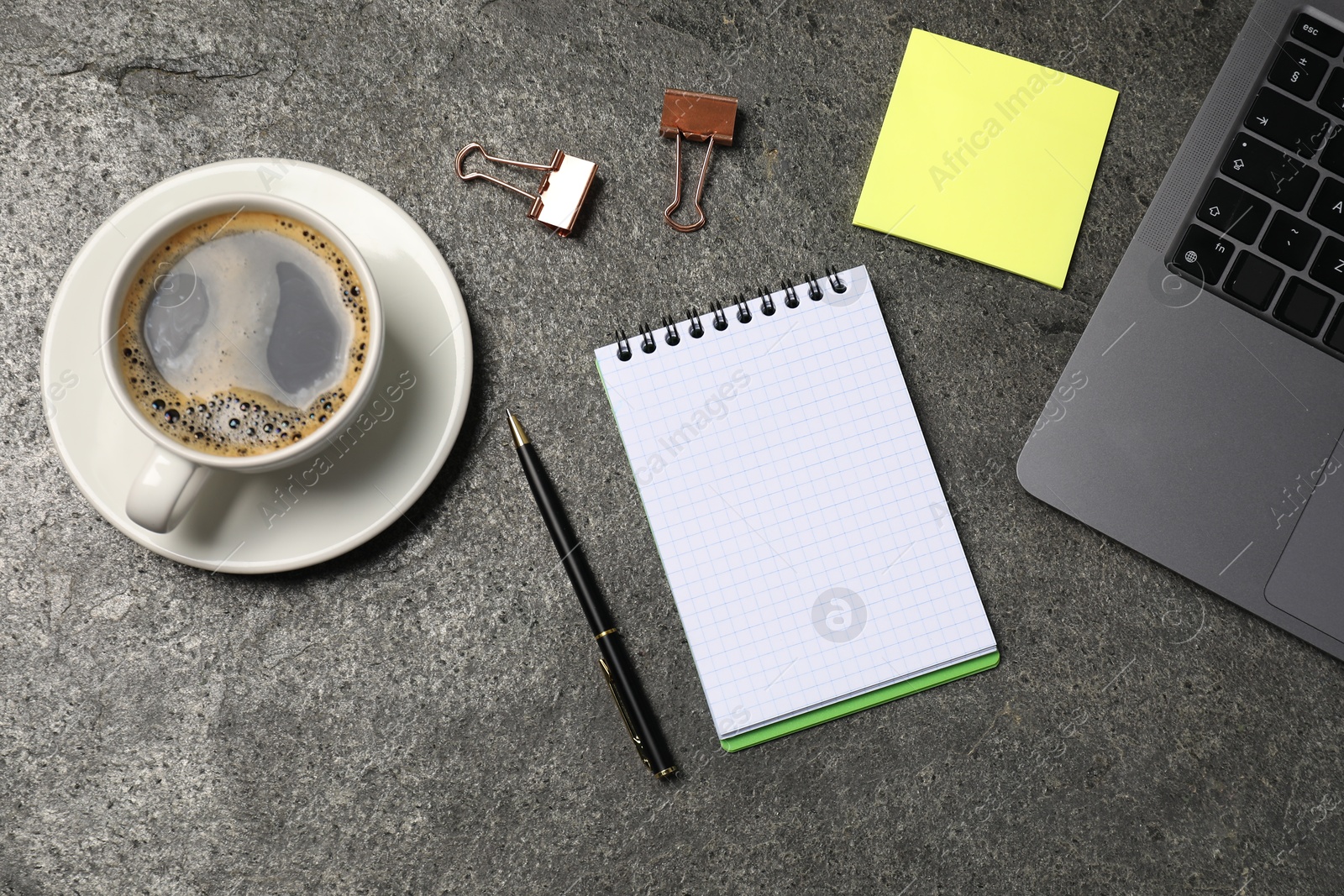 Notebook, pen, sticky note, coffee, binder clips, and laptop on grey table, flat lay Photo of Notebook, pen, sticky note, coffee, binder clips, and laptop on grey table, flat lay