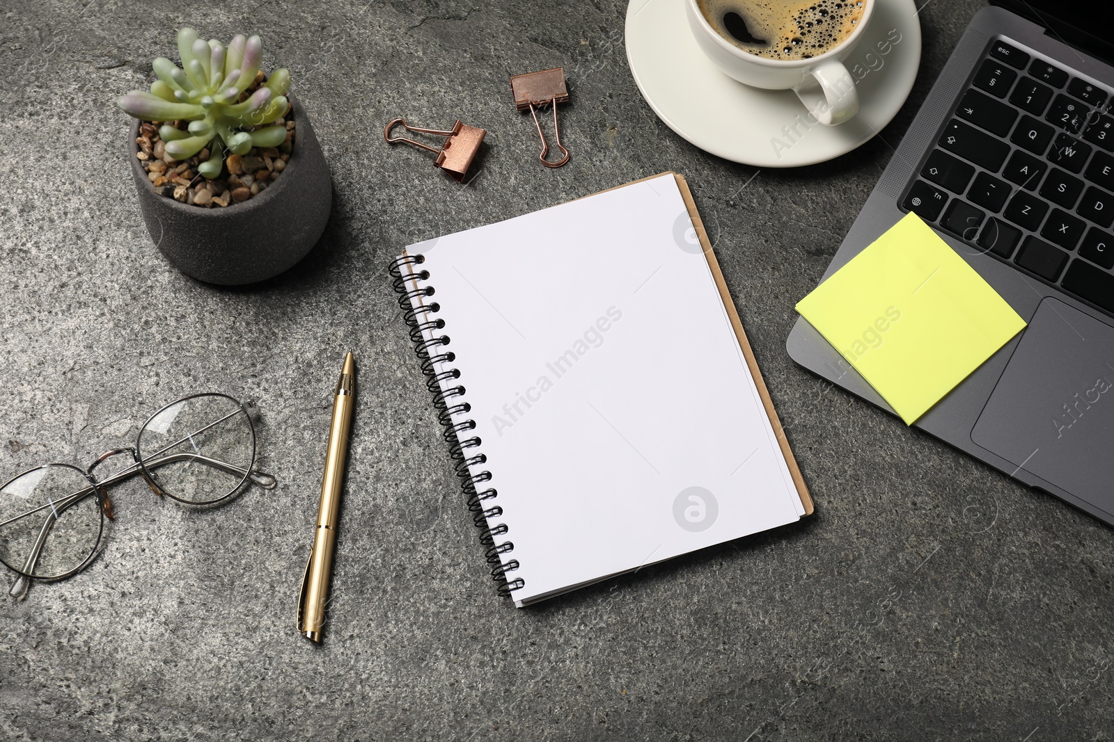 Notebook, pen, sticky note, coffee, glasses, floral decor and laptop on grey table, flat lay Photo of Notebook, pen, sticky note, coffee, glasses, floral decor and laptop on grey table, flat lay