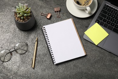 Photo of Notebook, pen, sticky note, coffee, glasses, floral decor and laptop on grey table, flat lay