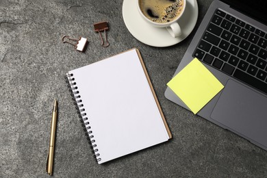 Photo of Notebook, pen, sticky note, coffee, binder clips, and laptop on grey table, flat lay