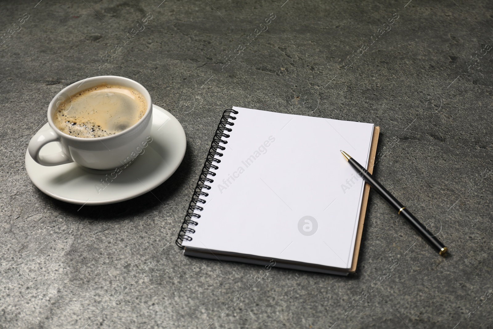 Notebook, pen and coffee on grey table, closeup Photo of Notebook, pen and coffee on grey table, closeup