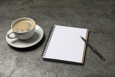 Photo of Notebook, pen and coffee on grey table, closeup