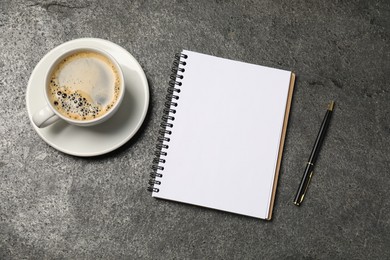 Photo of Notebook, pen and coffee on grey table, flat lay