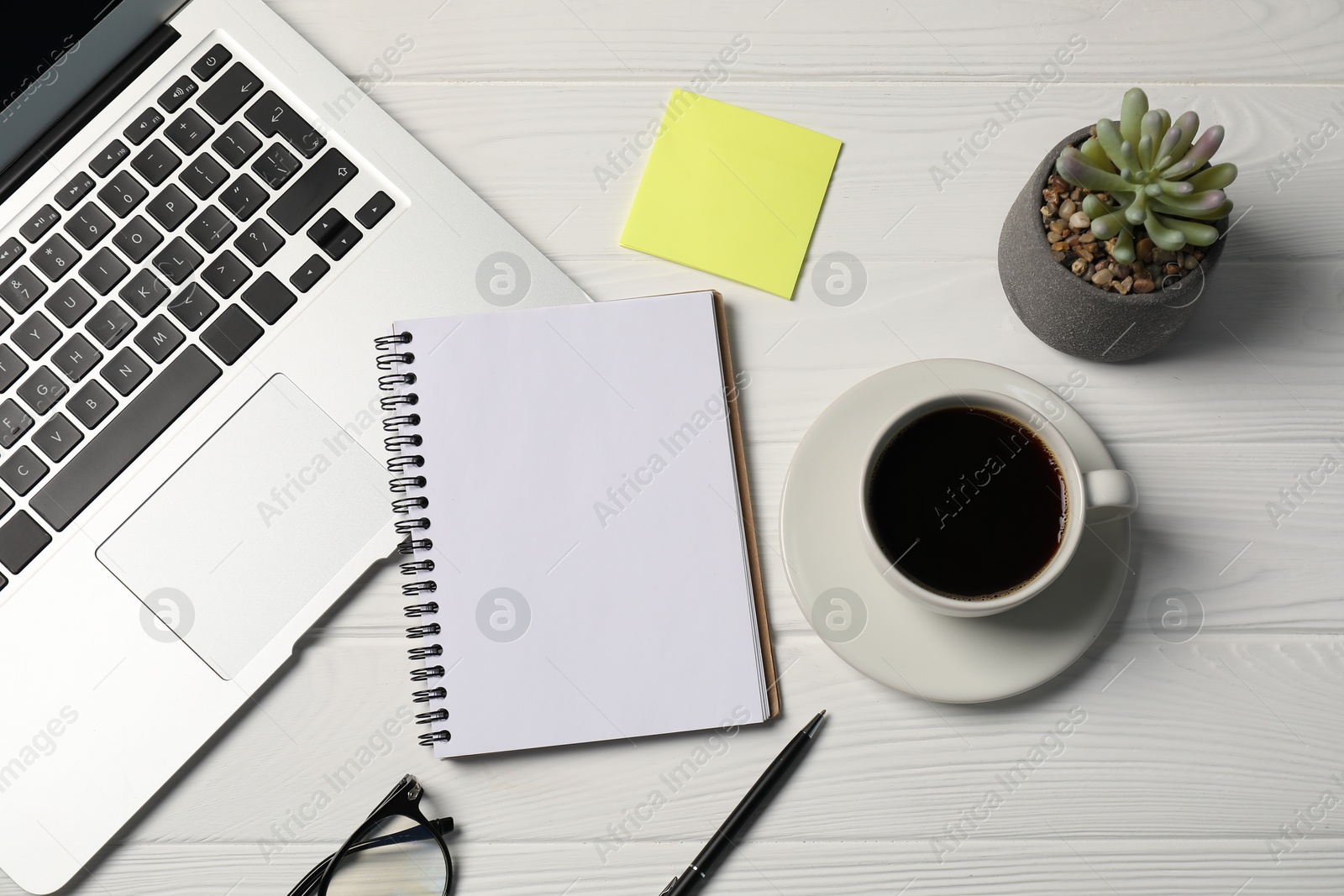 Photo of Notebook, pen, sticky note, coffee, floral decor and laptop on white wooden table, flat lay