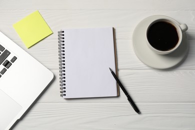 Photo of Notebook, pen, sticky note, coffee and laptop on white wooden table, flat lay