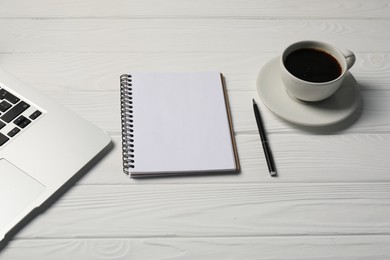 Photo of Notebook, pen, coffee and laptop on white wooden table