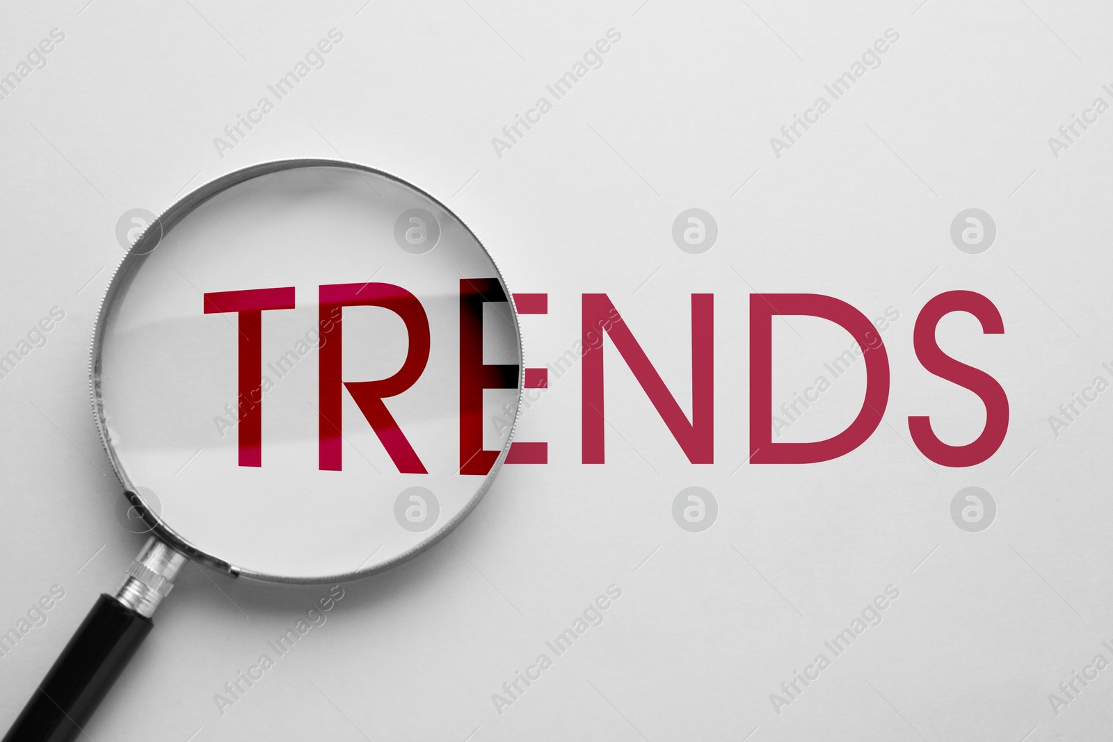 Word Trends and magnifying glass on white background, top view Image of Word Trends and magnifying glass on white background, top view
