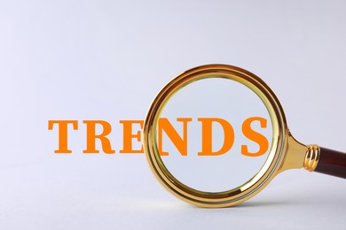 Image of Word Trends, view through magnifying glass on light grey background