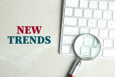 Image of New trends. Magnifying glass and computer keyboard on light table, top view